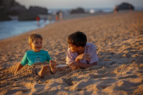 Dziecko Łaskotanie Rodzeństwa Plaży Nogach Piórem Dziecko Pokryte Piaskiem Uśmiech — Zdjęcie stockowe