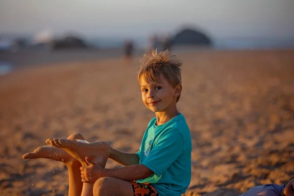 フェザーでビーチで兄弟姉妹をくすぐる 砂で子供カバー 笑って いくつかの楽しみを楽しむ — ストック写真