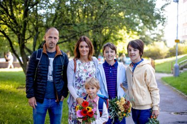 Birinci sınıf öğrencisi için okulda ilk gün, okula başlayan çocuk, öğretmen için çiçek getiriyor, aile üyeleri de onunla gidiyor.