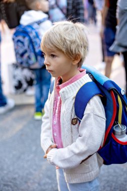 Birinci sınıf öğrencisi için okulda ilk gün, okula başlayan çocuk, öğretmen için çiçek getiriyor, aile üyeleri de onunla gidiyor.