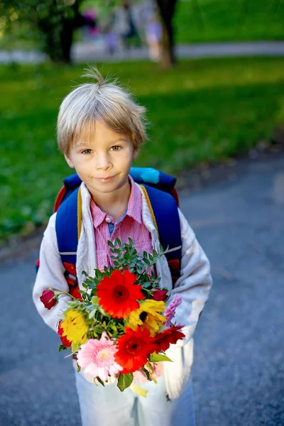 First day at school for a firstgraden, child starting school, bringing flowers for the teacher, family members going with him