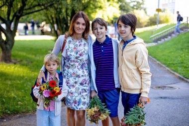Birinci sınıf öğrencisi için okulda ilk gün, okula başlayan çocuk, öğretmen için çiçek getiriyor, aile üyeleri de onunla gidiyor.