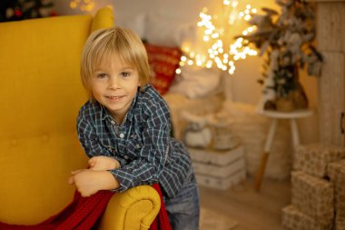 Sevimli çocuk, oğlum, Noel için süslü bir odada oynuyor, rahat bir yerde.