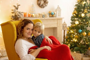 Sevimli çocuk, oğlum, Noel için süslü bir odada oynuyor, rahat bir yerde.