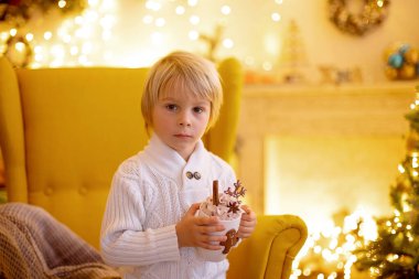 Tatlı çocuk, oğlum, Noel için süslü bir odada sarı bir koltukta oturuyor, rahat bir yer.