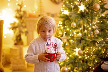 Tatlı çocuk, oğlum, Noel için süslü bir odada sarı bir koltukta oturuyor, rahat bir yer.