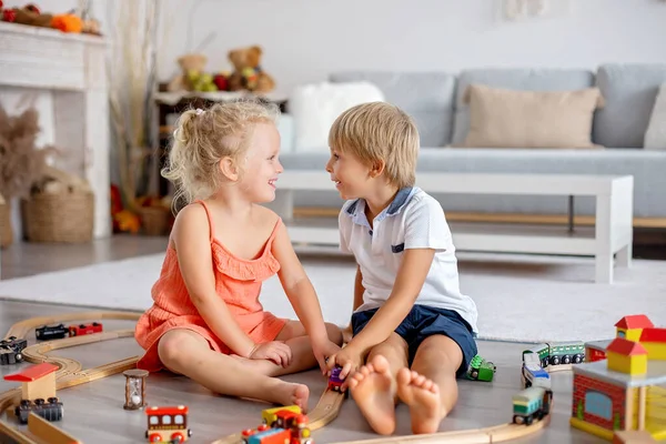 Two sweet children, siblings, playing with trains at home together