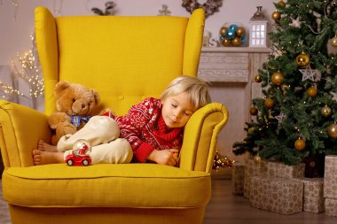 Sevimli çocuk, oğlum, Noel için süslü bir odada oynuyor, rahat bir yerde.