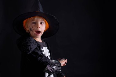 Cadılar Bayramı için giyinmiş, evde oynayan, siyah arka planda izole edilmiş bir çocuk.