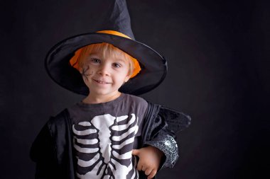 Cadılar Bayramı için giyinmiş, evde oynayan, siyah arka planda izole edilmiş bir çocuk.