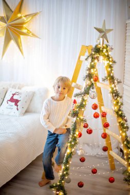 Güzel sarışın çocuk, genç okul çocuğu, Noel 'de süslü bir evde örülmüş oyuncaklarla oynuyor.