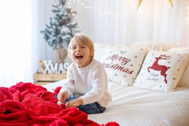 Güzel sarışın çocuk, genç okul çocuğu, Noel 'de süslü bir evde örülmüş oyuncaklarla oynuyor.