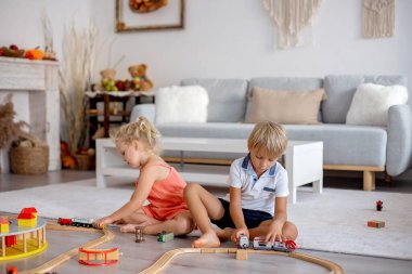 İki tatlı çocuk, kardeşler, evde trenlerle oynuyorlar.