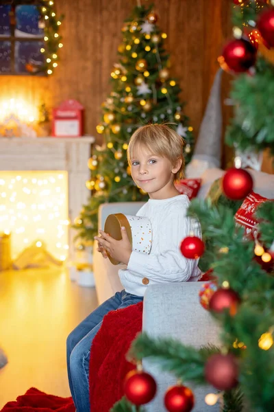 美しいブロンドの子供 若い学校の少年 クリスマスに編まれたおもちゃで装飾された家で遊ぶ — ストック写真