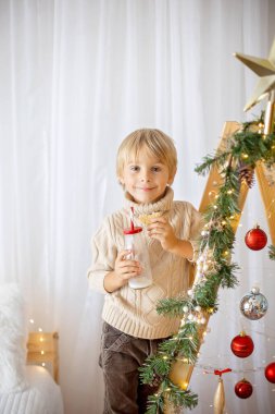 Güzel sarışın çocuk, genç okul çocuğu, Noel 'de süslü bir evde örülmüş oyuncaklarla oynuyor.