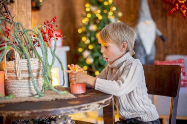 Güzel sarışın çocuk, genç okul çocuğu, Noel 'de süslü bir evde örülmüş oyuncaklarla oynuyor.