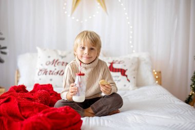 Güzel sarışın çocuk, genç okul çocuğu, Noel 'de süslü bir evde örülmüş oyuncaklarla oynuyor.