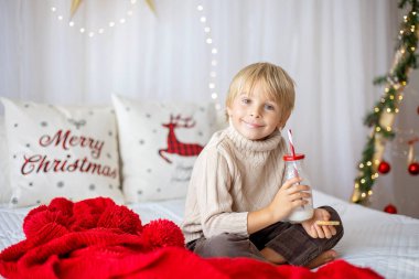 Güzel sarışın çocuk, genç okul çocuğu, Noel 'de süslü bir evde örülmüş oyuncaklarla oynuyor.