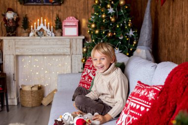 Güzel sarışın çocuk, genç okul çocuğu, Noel 'de süslü bir evde örülmüş oyuncaklarla oynuyor.