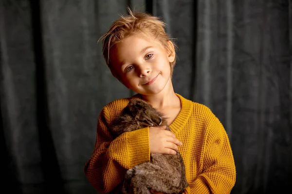 美しい小さなブロンドの子供 かわいい男の子 小さなペットウサギを抱き 家で抱きしめる — ストック写真