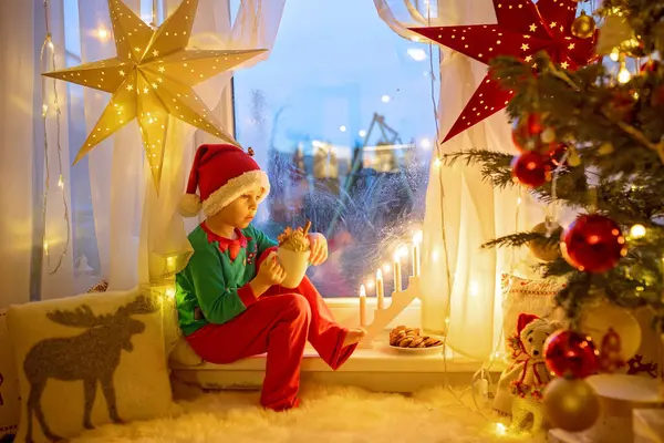 Małe Dziecko Uroczy Blondyn Siedzący Oknie Piżamie Patrzący Satnego Mikołaja — Zdjęcie stockowe