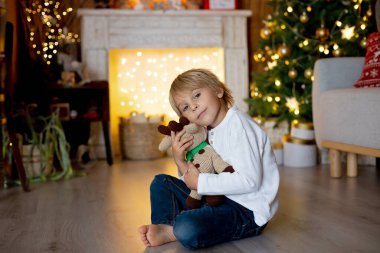 Güzel sarışın çocuk, genç okul çocuğu, Noel 'de süslü bir evde örülmüş oyuncaklarla oynuyor.