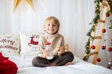 Güzel sarışın çocuk, genç okul çocuğu, Noel 'de süslü bir evde örülmüş oyuncaklarla oynuyor.