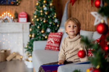 Güzel sarışın çocuk, genç okul çocuğu, Noel 'de süslü bir evde örülmüş oyuncaklarla oynuyor.