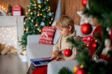 Güzel sarışın çocuk, genç okul çocuğu, Noel 'de süslü bir evde örülmüş oyuncaklarla oynuyor.