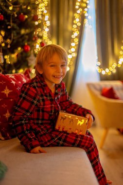 Güzel sarışın çocuk, genç okul çocuğu, süslü bir evde okul için ödev yazıyor, süt içiyor ve kurabiye yiyor. Işıklar ve örgü oyuncaklar