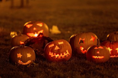 Parkta Cadılar Bayramı kostümlü iki çocuk mum ve dekorasyonla balkabağı oyup oynuyorlar.