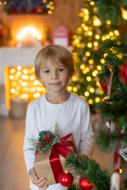 Güzel sarışın çocuk, genç okul çocuğu, süslü bir evde okul için ödev yazıyor, süt içiyor ve kurabiye yiyor. Işıklar ve örgü oyuncaklar