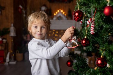 Güzel sarışın çocuk, genç okul çocuğu, süslü bir evde okul için ödev yazıyor, süt içiyor ve kurabiye yiyor. Işıklar ve örgü oyuncaklar