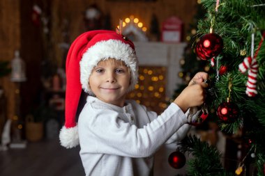Güzel sarışın çocuk, genç okul çocuğu, süslü bir evde okul için ödev yazıyor, süt içiyor ve kurabiye yiyor. Işıklar ve örgü oyuncaklar