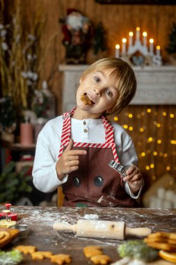 Güzel sarışın çocuk, genç okul çocuğu, süslü bir evde okul için ödev yazıyor, süt içiyor ve kurabiye yiyor. Işıklar ve örgü oyuncaklar