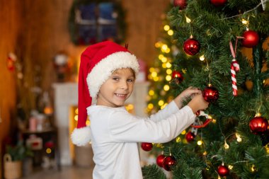 Güzel sarışın çocuk, genç okul çocuğu, süslü bir evde okul için ödev yazıyor, süt içiyor ve kurabiye yiyor. Işıklar ve örgü oyuncaklar