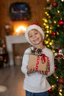 Güzel sarışın çocuk, genç okul çocuğu, süslü bir evde okul için ödev yazıyor, süt içiyor ve kurabiye yiyor. Işıklar ve örgü oyuncaklar