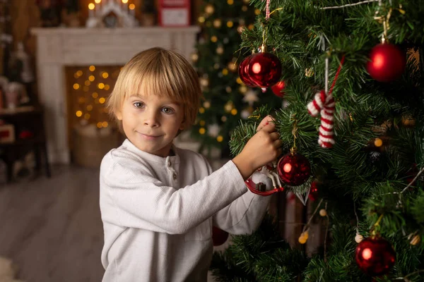 Güzel sarışın çocuk, genç okul çocuğu, süslü bir evde okul için ödev yazıyor, süt içiyor ve kurabiye yiyor. Işıklar ve örgü oyuncaklar