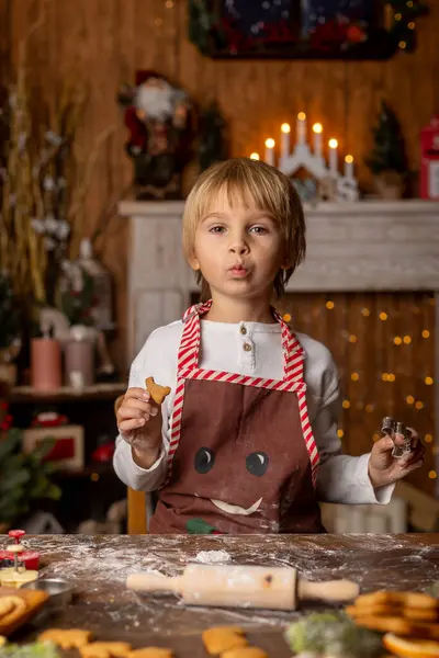 美しい金髪の子供 若い学校の少年は 装飾された家で学校の宿題を書き 牛乳を飲んでクッキーを食べました リグスとニットのおもちゃの周り — ストック写真