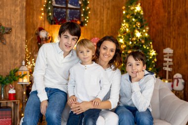 Mutlu bir aile, çocuklar ve anne, sıcak bir Noel stüdyosunda aile fotoğrafları çekiyorlar.