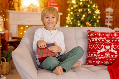 Güzel sarışın çocuk, genç okul çocuğu, süslü bir evde okul için ödev yazıyor, süt içiyor ve kurabiye yiyor. Işıklar ve örgü oyuncaklar