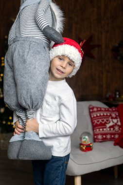 Güzel sarışın çocuk, genç okul çocuğu, süslü bir evde okul için ödev yazıyor, süt içiyor ve kurabiye yiyor. Işıklar ve örgü oyuncaklar