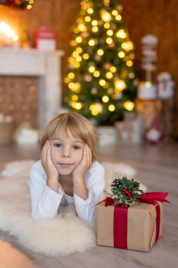 Güzel sarışın çocuk, genç okul çocuğu, süslü bir evde okul için ödev yazıyor, süt içiyor ve kurabiye yiyor. Işıklar ve örgü oyuncaklar