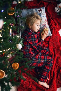 Tatlı çocuk, tatlı sarışın çocuk, Noel ağacının altında uyuyor, Noel Baba 'nın gelmesini bekliyor.