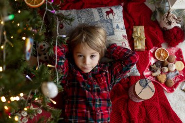 Tatlı çocuk, tatlı sarışın çocuk, Noel ağacının altında uyuyor, Noel Baba 'nın gelmesini bekliyor.