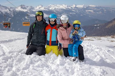 Mutlu aile, çocuklarla kayak tatili, açık havada güneşli güzel hava.