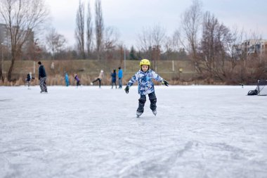 Mutlu çocuk, çocuk, gün boyunca donmuş gölde paten kaymak, dışarıda eğlenmek.