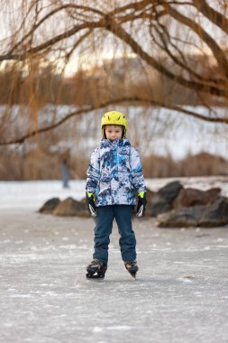 Mutlu çocuk, çocuk, gün boyunca donmuş gölde paten kaymak, dışarıda eğlenmek.