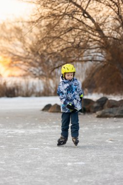 Mutlu çocuk, çocuk, gün boyunca donmuş gölde paten kaymak, dışarıda eğlenmek.