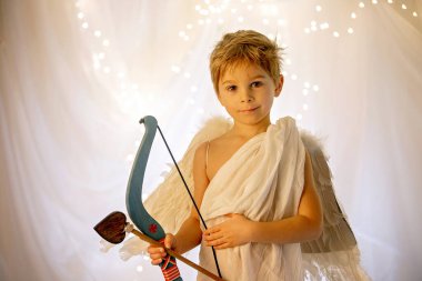 Little cupid toddle boy, holding bow and arrow, beautiful blond cherub, love